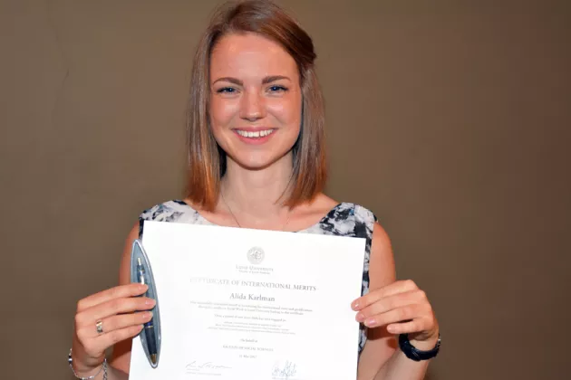 Alida Karlman holding up her Certificate of International Merits