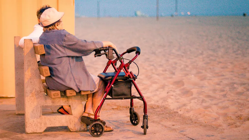 Foto. Äldre par med rullator på strandbänk. Foto: Oxana Melis.
