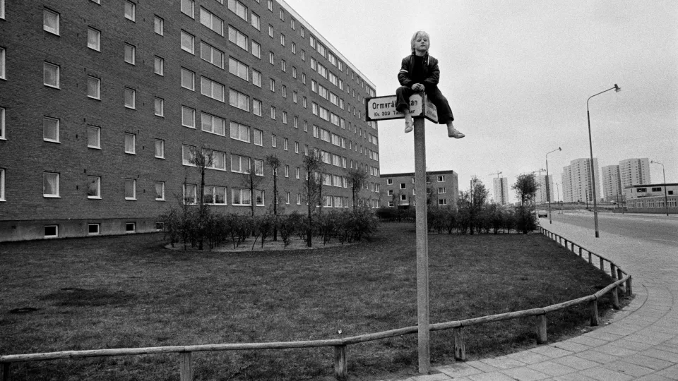 Foto. Pojke som sitter uppflugen på gatuskylt. Söderkulla, Malmö 1972.