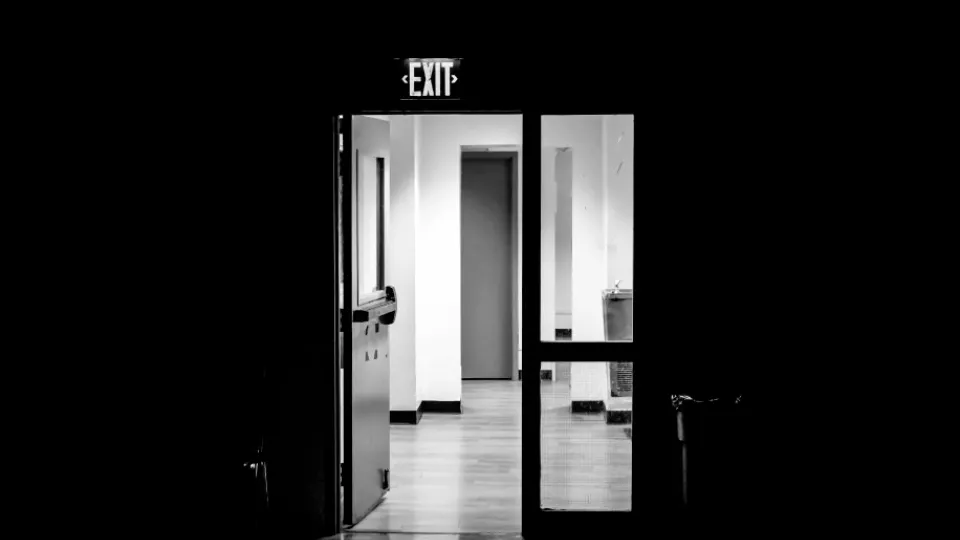 Bildillustration: En öppen dörr i en mörk korridor. Det finns ljus längre ner i korridoren.
