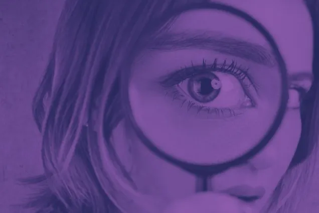 En kvinna som håller ett förstoringsglas framför ögat.